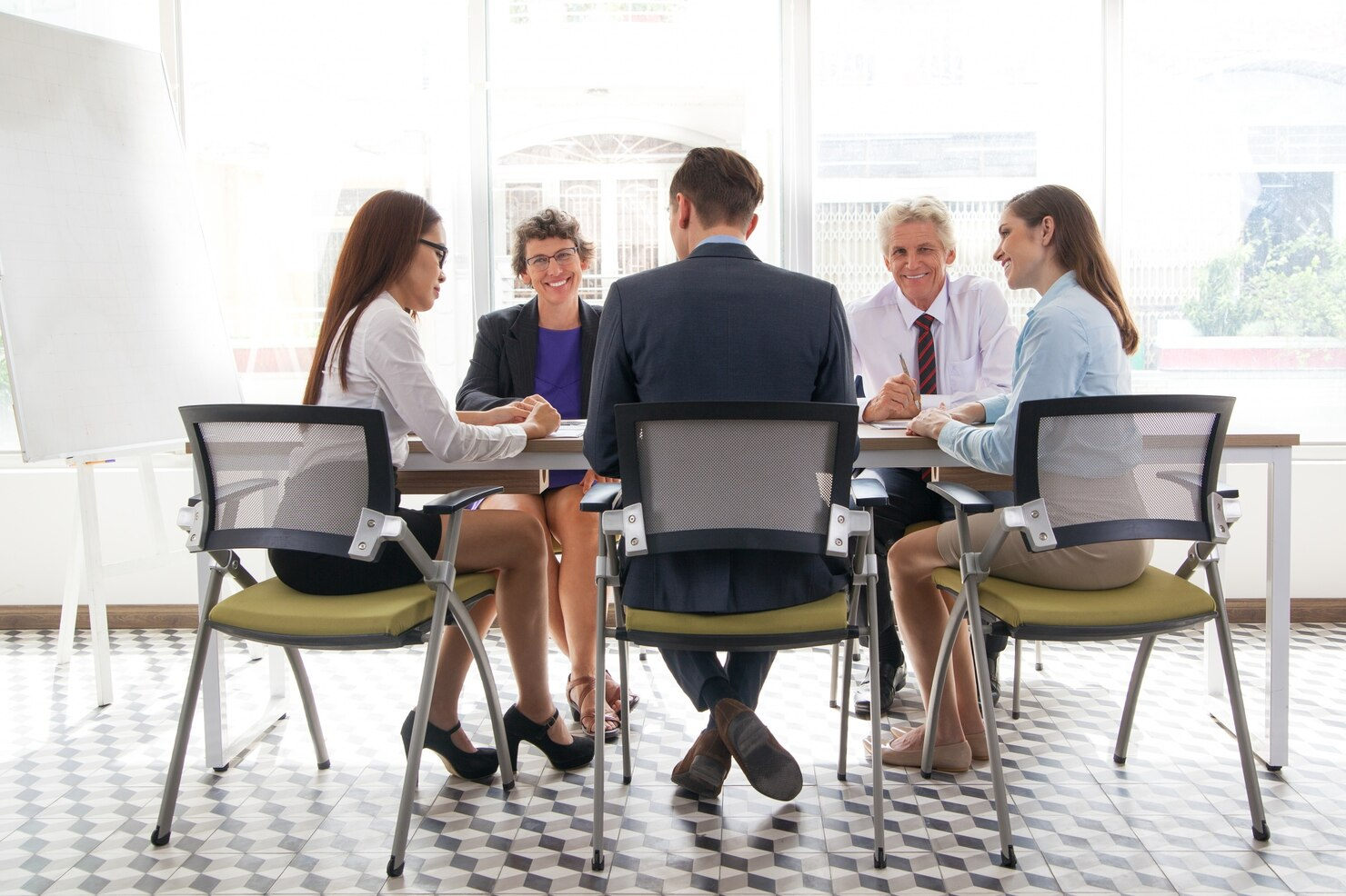 A leadership team meeting around a table in a bright office.
