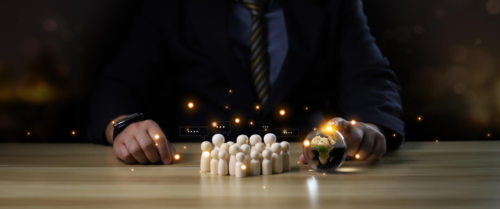 A leader in a dark suit arranging white wooden figures.